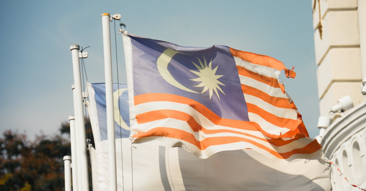 A vibrant Malaysian flag waving against a clear blue sky symbolizes national pride and patriotism.